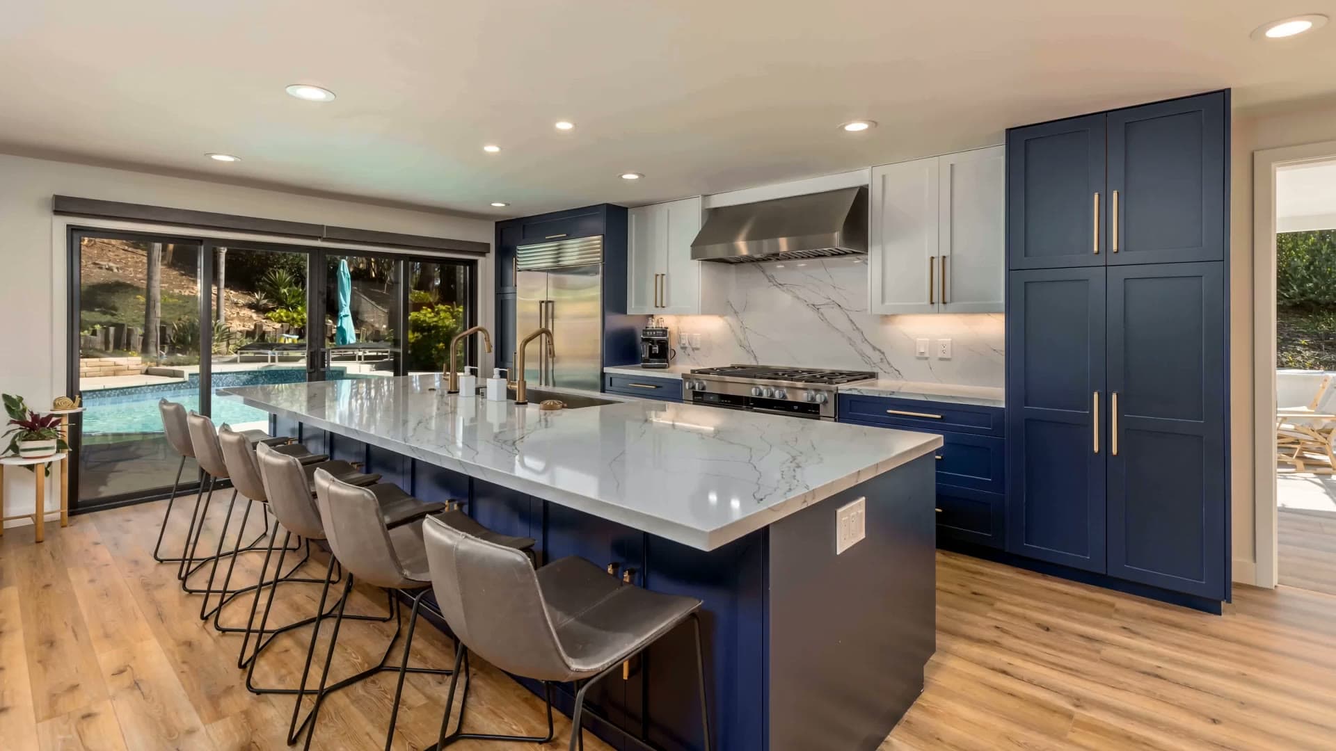 Teknik Design & Remodeling hero — luxury blue-island kitchen with marble waterfall countertop and poolside views in San Diego