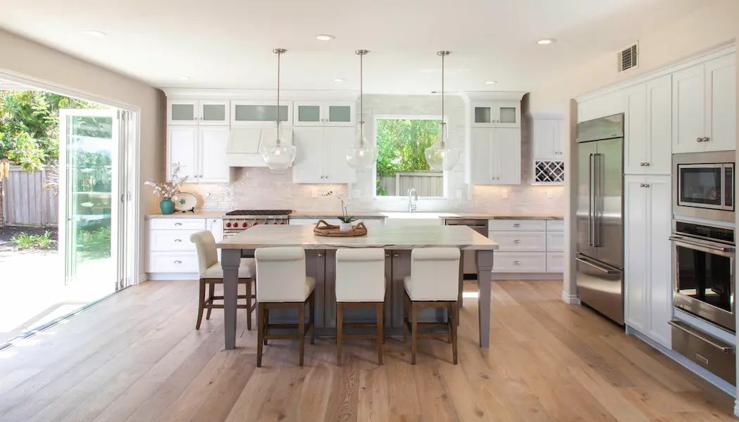 Bright kitchen in Carlsbad with glass doors, wide plank floors and modern pendant lighting
