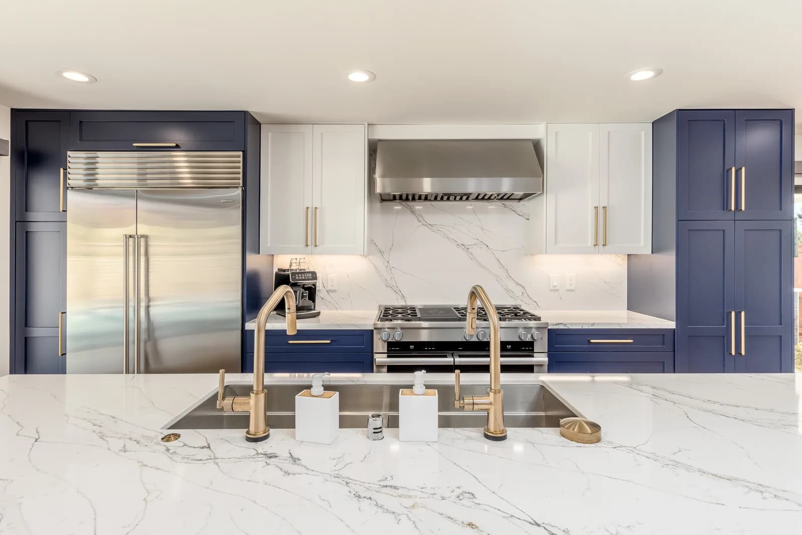 Navy and white marble chef kitchen with brass fixtures after whole house remodel in Scripps Ranch