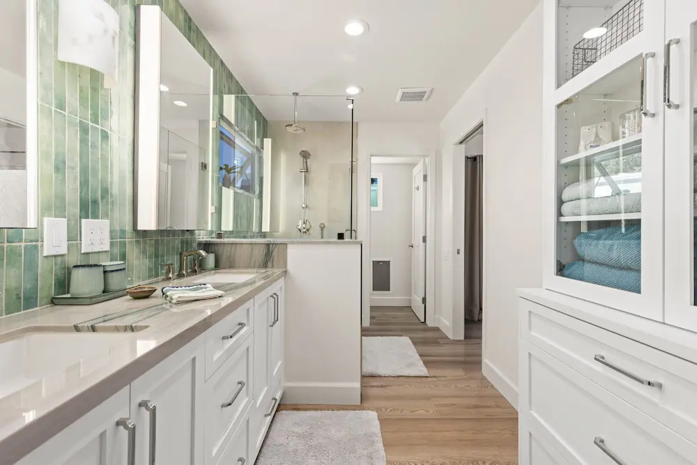 bathroom remodel with green tile backsplash white vanity and glass shower enclosure